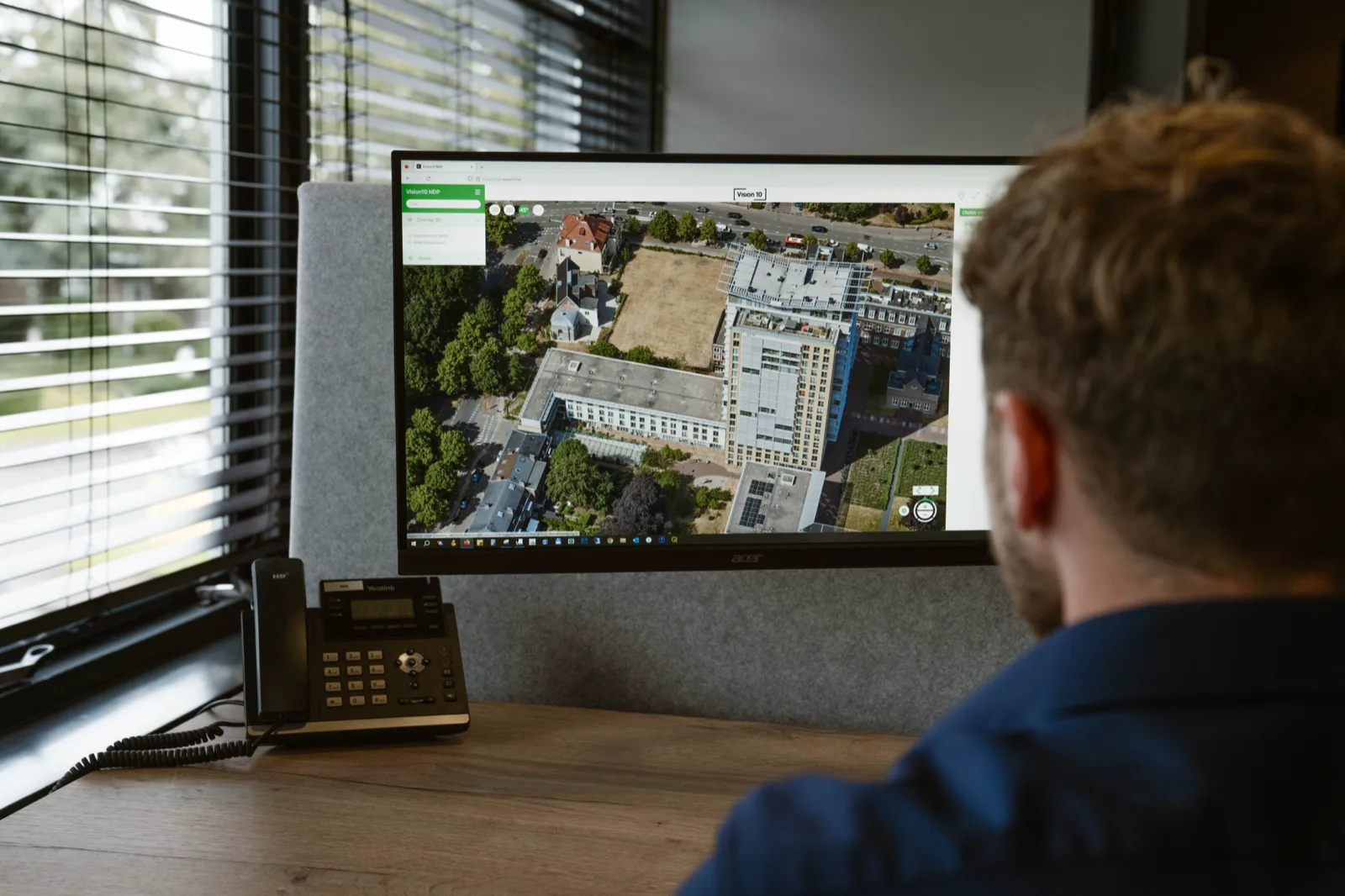 Specialist bekijkt oblieke luchtfoto in Vision 10 — schuine opname van een stedelijk gebied direct raadpleegbaar via de browser